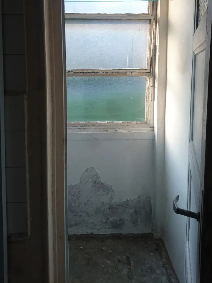 Ancienne salle d’eau dégradée, enduit cloqué par l’humidité